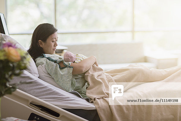 Mother cradling newborn baby in hospital room