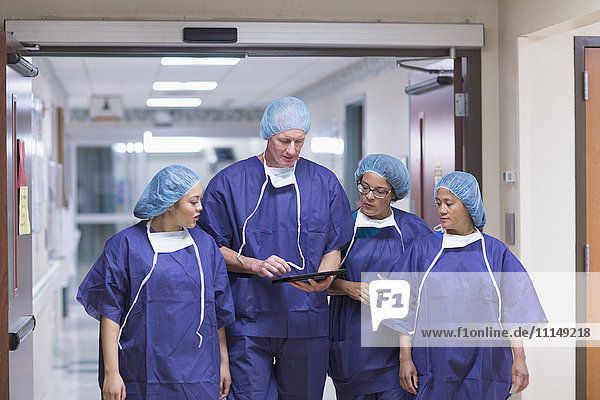 Surgeons using digital tablet in hospital hallway