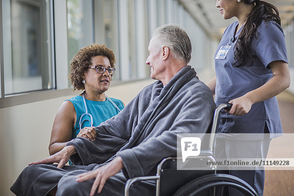 Arzt spricht mit Patient im Rollstuhl
