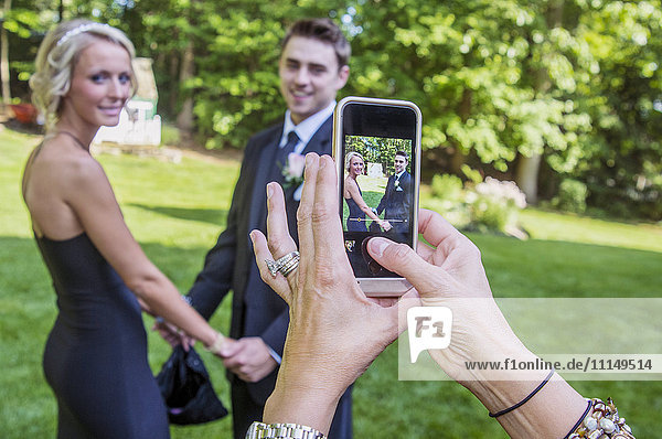 Frau fotografiert Paar mit ihrem Handy