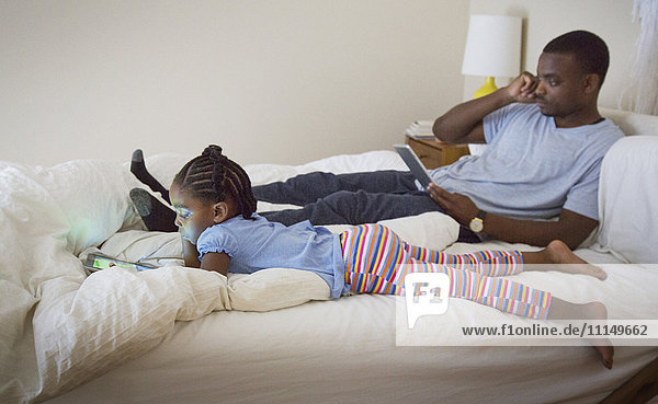 African American father and daughter relaxing on bed