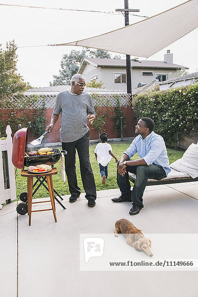 Afroamerikanischer Vater und Sohn unterhalten sich beim Grillen