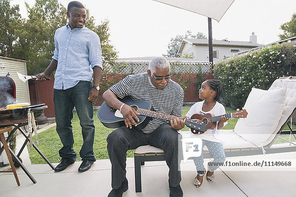 Afroamerikanischer Großvater bringt seiner Enkelin das Gitarrenspiel bei
