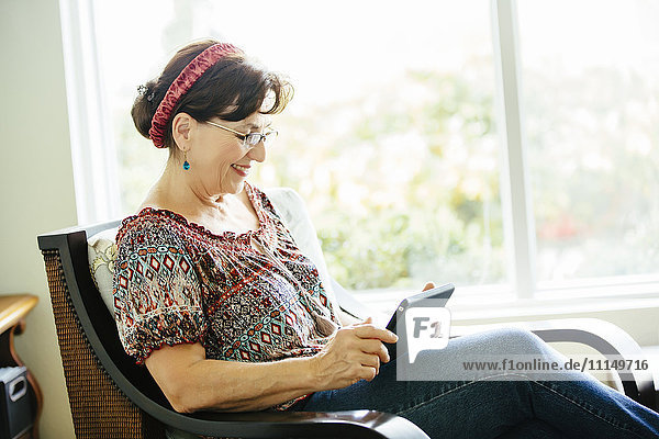Kaukasische Frau mit digitalem Tablet im Sessel