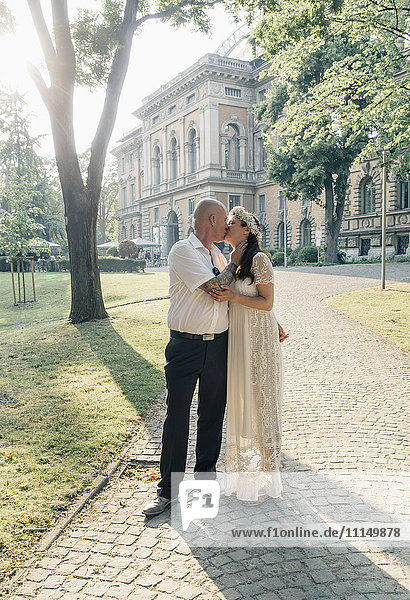 Kaukasisches frisch verheiratetes Paar küsst sich im Freien