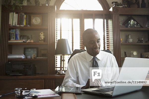Black doctor using laptop in office