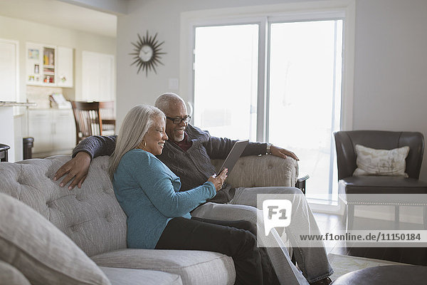 Older couple using digital tablet on sofa
