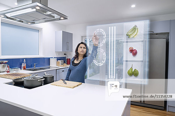 Gemischtrassige Frau mit holografischem Bildschirm in der Küche