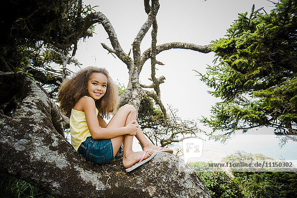 Mixed race girl smiling on rock