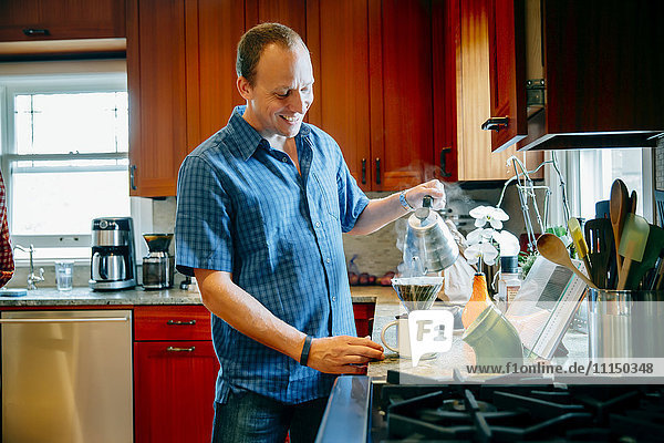 Kaukasischer Mann gießt Kaffee in der Küche ein