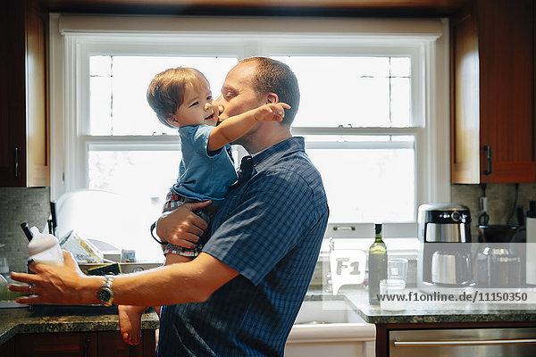 Vater küsst Babysohn in der Küche