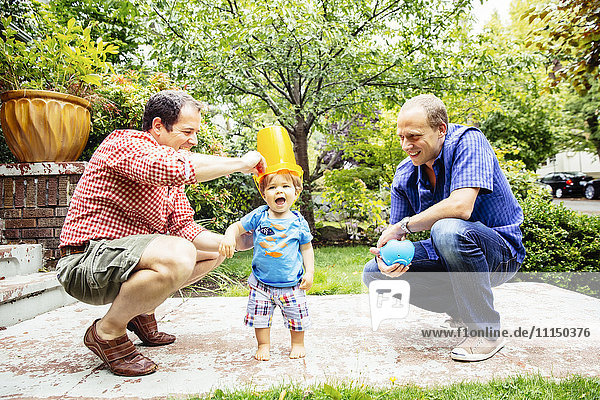 Schwule Väter spielen mit ihrem kleinen Sohn im Freien