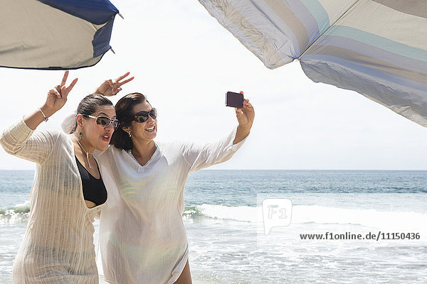 Hispanische Frauen machen Handy-Selfie am Strand