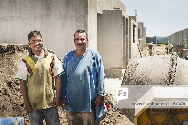 Lächelnde hispanische Bauarbeiter auf der Baustelle