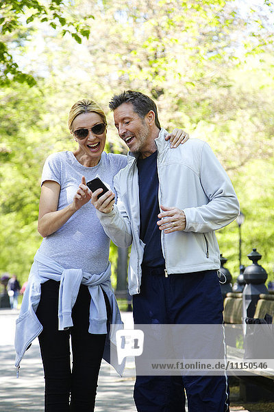Caucasian couple using cell phone in park