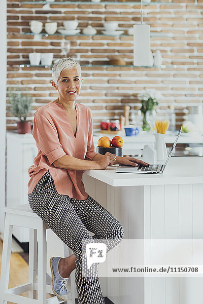 Older Caucasian woman using laptop in kitchen