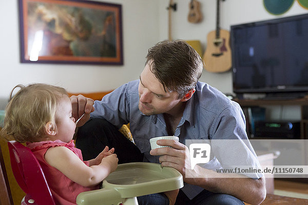Caucasian father feeding toddler daughter