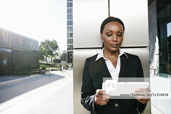 Schwarze Geschäftsfrau benutzt digitales Tablet im Freien