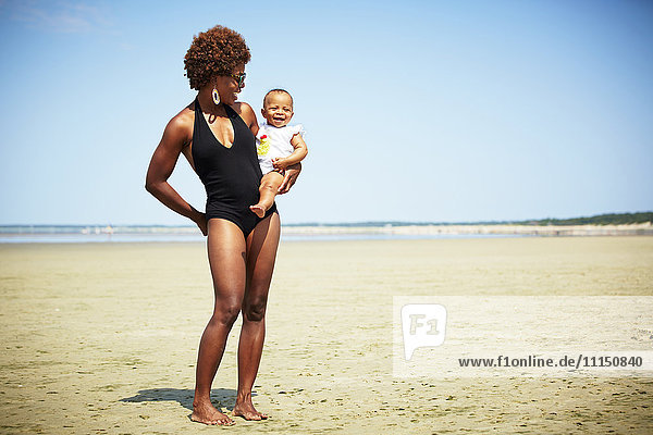 Smiling mother holding girl on beach