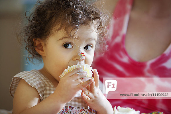 Messy baby girl eating cupcake