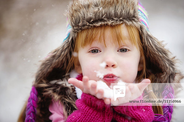 Caucasian girl blowing handful of snow