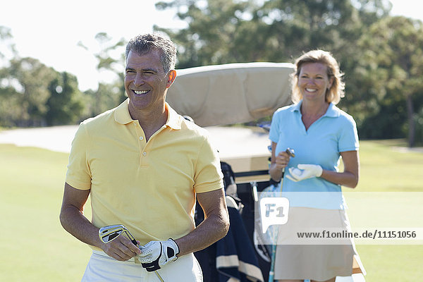 Caucasian couple playing golf on course