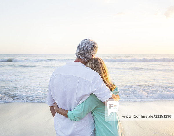 Caucasian couple hugging on beach