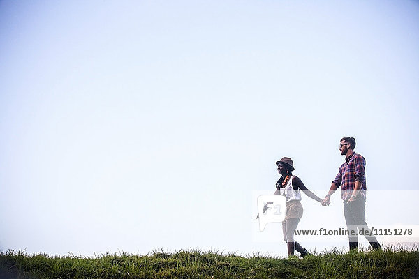 Paar spaziert zusammen in einem grasbewachsenen Feld