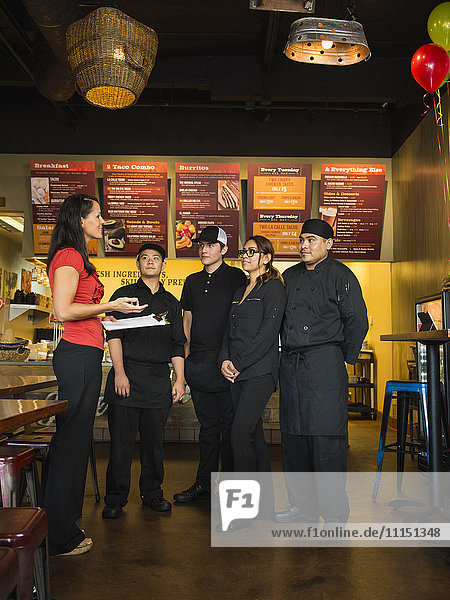 Hispanischer Geschäftsinhaber und Angestellte im Gespräch in einem Cafe