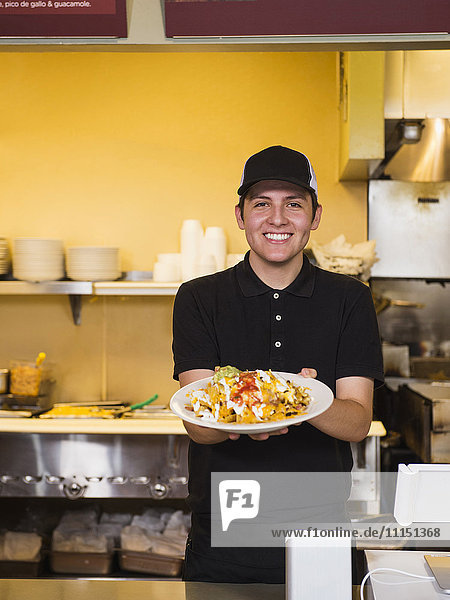 Hispanic server holding food in cafe