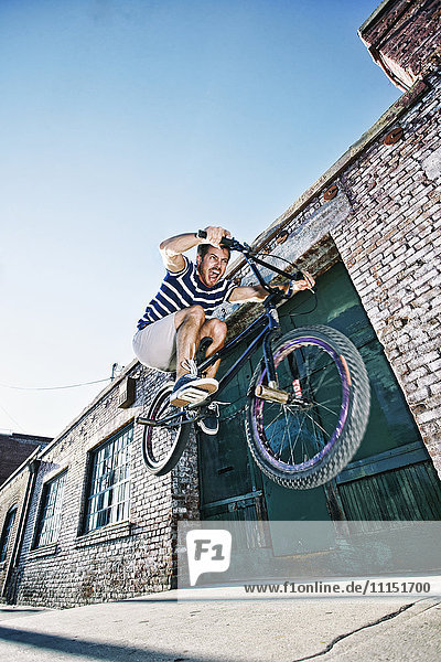 Kaukasischer Mann springt auf BMX-Rad