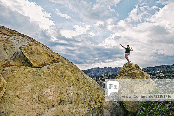 Gemischtrassige Frau klettert auf Felsformation