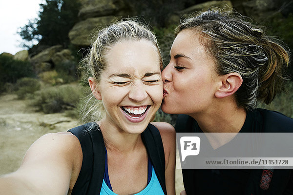 Woman kissing cheek of friend outdoors