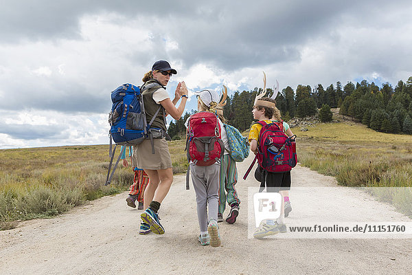 Caucasian hiker leading children on path in remote landscape