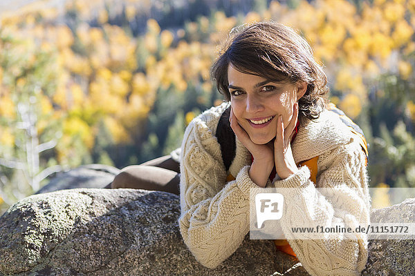Gemischtrassige Frau lächelnd auf Felsen