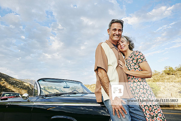 Lächelndes Paar in der Nähe eines klassischen Cabriolets