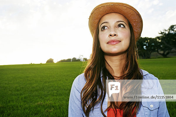 Hispanische Frau lächelnd auf einem grasbewachsenen Feld