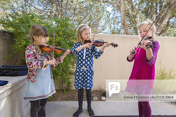 Girls playing violin outdoors