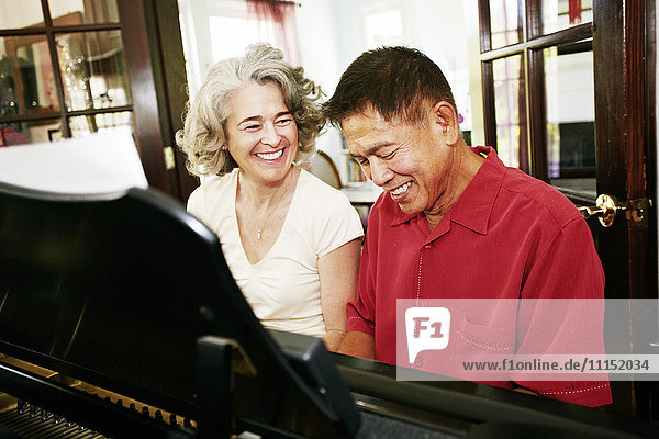 Ehepaar spielt zusammen im Wohnzimmer Klavier