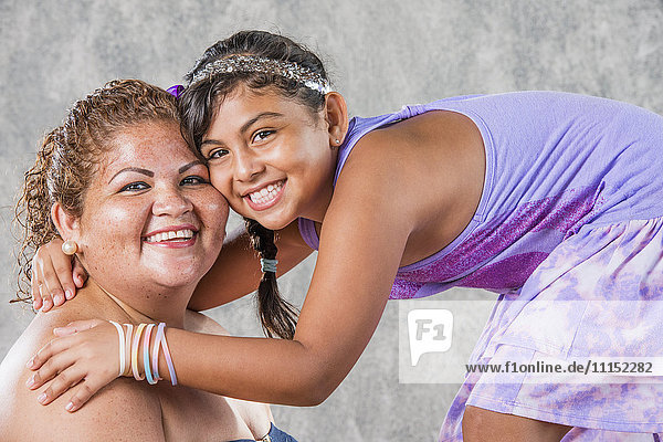 Lächelnde hispanische Mutter und Tochter  die sich umarmen