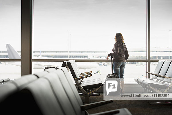 Hispanische Frau schaut aus dem Flughafenfenster