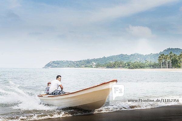 Mann steuert Boot auf den Strand