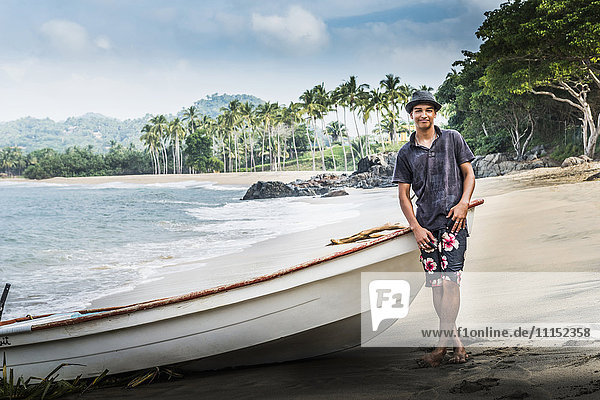 Hispanic man standing near boat on beach