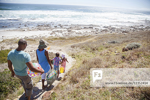 Mixed race family walking on path to beach