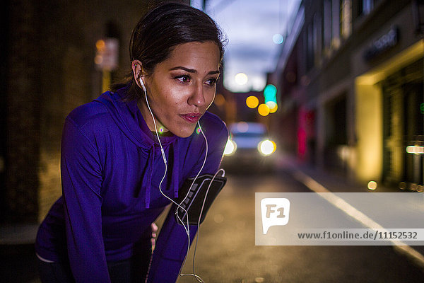 Hispanischer Läufer  der sich nachts auf einer Straße ausruht