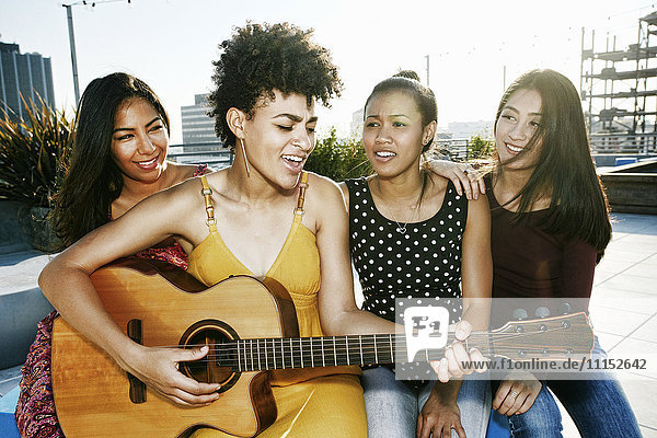 Musizierende und singende Frauen auf dem Dach einer Stadt