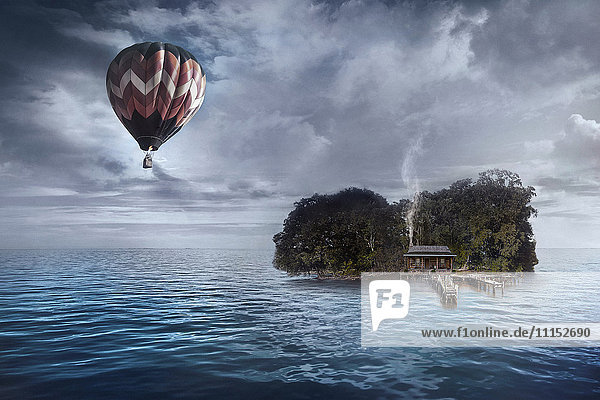 Heißluftballon schwebt über einem Haus auf einer tropischen Insel