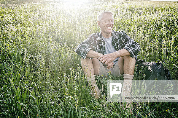Older Caucasian man sitting on grassy hillside