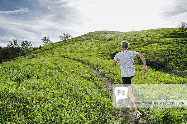 Älterer kaukasischer Mann joggt auf einem Feldweg