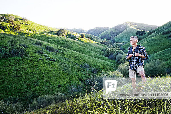 Older Caucasian man smiling on grassy hillside